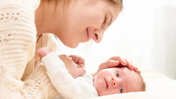 Closeup portrait of loving young mother stroking her 1 months old baby boy lying on bed. Concept of family happiness and loving parents with little children — Stock Photo, Image