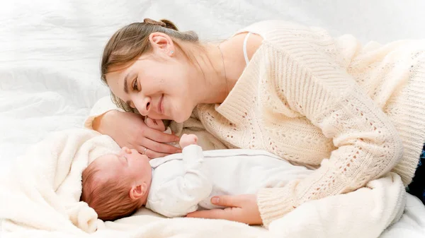 Widok z góry piękny uśmiechnięty matka leżąca obok jej noworodka i patrząc na syna. Pojęcie szczęścia rodzinnego i kochających rodziców z małymi dziećmi — Zdjęcie stockowe