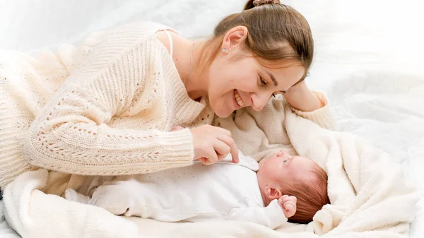幸せな笑顔の女性のポートレート小さな新生児とともに柔らかいベッドの上に横たわっ午前中 — ストック写真