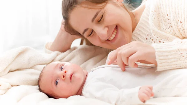 Porträt einer fröhlich lächelnden und lachenden jungen Mutter, die mit ihrem kleinen Sohn im Bett spielt. Konzept des Familienglücks und liebevoller Eltern mit kleinen Kindern — Stockfoto