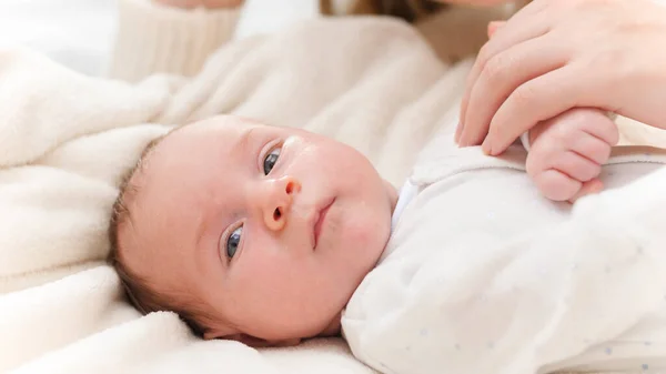 Porträt eines entzückenden Neugeborenen und einer glücklich lächelnden Mutter. Mutter kitzelt und spielt mit Kind in Krippe Konzept des Familienglücks und liebevoller Eltern mit kleinen Kindern — Stockfoto