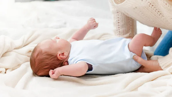 Ung omtänksam mor hålla och lyfta upp hennes nyfödda son liggande i sängen. Begreppet familj lycka och kärleksfulla föräldrar med små barn — Stockfoto