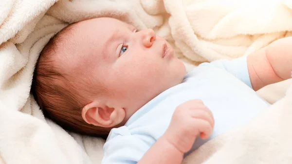 Vista acima em adorável bebê recém-nascido coberto de cobertor macio deitado no berço. — Fotografia de Stock