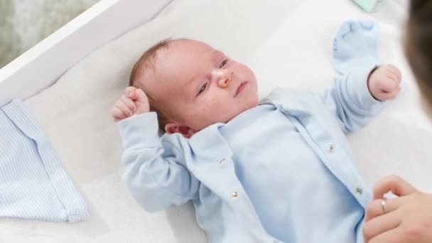 Ovanifrån av ung mor klä av sin lilla son liggande på skötbord för att byta hans smutsiga kläder. Begreppet spädbarn och nyfödd hygien och hälsovård. Vårdande föräldrar med små barn. — Stockvideo