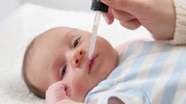 Annenin yeni doğan oğluna göz damlasından D vitamini ve K vitamini vermesine yakın çekim. Bebekler, yeni doğan aşılar ve sağlık hizmetleri kavramı. Küçük çocukları olan ilgili ebeveynler..