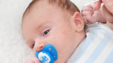 Kulak kirinden pamuk çubuğuyla yeni doğmuş bebek kulaklarını temizleme. Bebekler, yeni doğan hijyen ve sağlık hizmetleri kavramı. Küçük çocukları olan ilgili ebeveynler..