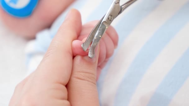 Großaufnahme einer Mutter, die ihrem kleinen Baby mit einer Schere lange Fingernägel abschneidet. Konzept der Baby- und Neugeborenenhygiene und Gesundheitsfürsorge. Fürsorgliche Eltern mit kleinen Kindern. — Stockvideo