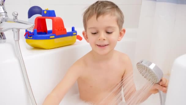Şirin küçük çocuk köpükle banyo yapıyor ve oyuncaklarla oynuyor. Evde çocuk hijyeni ve sağlık hizmetleri kavramı — Stok video