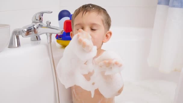 Vtipný chlapec se koupe a hraje si s mýdlovou pěnou. Koncept dětské hygieny a zdravotní péče doma. Děti se baví a hrají si — Stock video