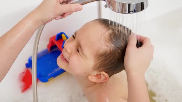 Großaufnahme einer fürsorglichen Mutter, die ihren kleinen Sohn mit Shampoo und Wasser wäscht. Konzept der Kinderhygiene und Gesundheitsfürsorge zu Hause. Familie hat Zeit zusammen und spielt zu Hause — Stockvideo