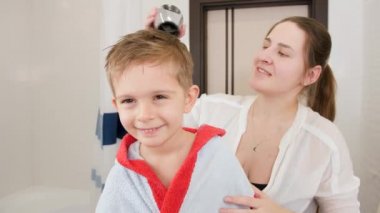 Anne ve küçük çocuğun banyo yaptıktan sonra saç kurutma makinesiyle saç kurutma portresi. Evde çocuk hijyeni ve sağlık hizmetleri kavramı. Evde ebeveynlere ve çocuklara bakmak.