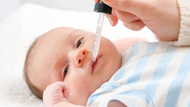 Annenin yeni doğan oğluna göz damlasından D vitamini ve K vitamini vermesine yakın çekim. Bebekler, yeni doğan aşılar ve sağlık hizmetleri kavramı. Küçük çocukları olan ilgili ebeveynler..
