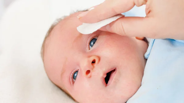 柔らかい綿のパッドで掃除や洗濯の赤ちゃんの顔の閉鎖。赤ちゃんと新生児の衛生と医療の概念。小さな子供を持つ親の世話. — ストック写真