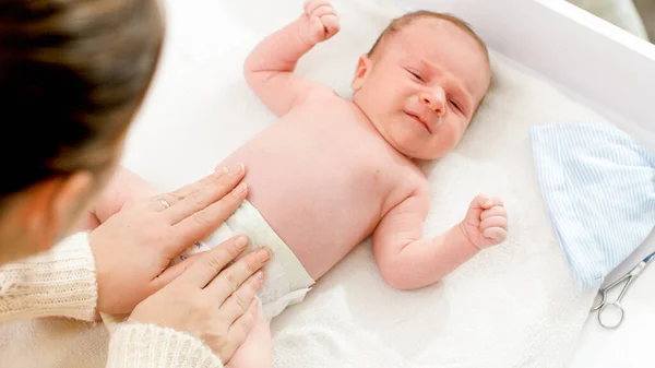 Madre joven cambiando pañales desordenados a su hijo recién nacido —  Fotos de Stock