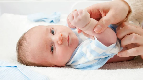 Retrato del pequeño bebé recién nacido sonriente acostado en la cuna y sosteniendo el dedo de las madres — Foto de Stock