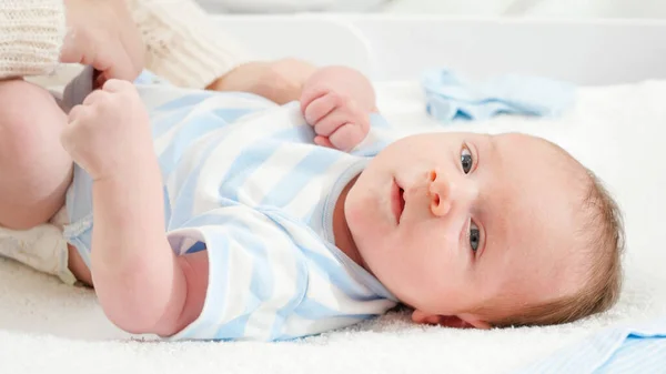 Mor klär på sin lille son som ligger på skötbordet hemma. Begreppet spädbarn och nyfödd hygien och hälsovård. Vårdande föräldrar med små barn. — Stockfoto