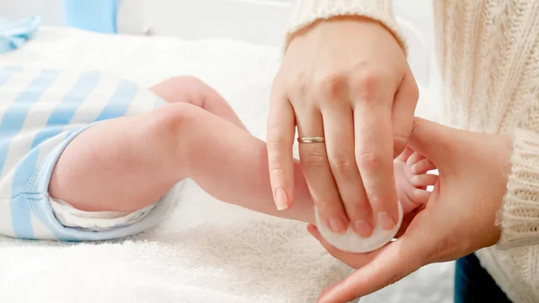 Primer plano de la madre limpiando el cuerpo del bebé recién nacido y aplicando aceite hidratante para bebés con almohadilla de algodón — Foto de Stock