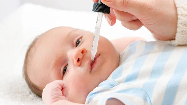 Närbild av mor ger vitamin D och K till hennes nyfödda son från eyedropper. Begreppet spädbarn och nyfödda vaccinationer och hälsovård. Vårdande föräldrar med små barn. — Stockfoto