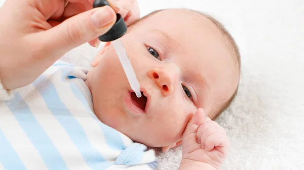 Closeup of giving vaccine to newborn baby boy from eyedropper or syringe. Concept of babies and newborn vaccination and giving vitamins. Caring parents with little children.