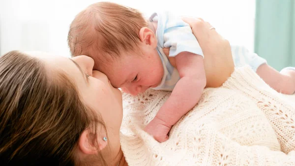 Porträt eines kleinen neugeborenen Jungen, der auf einer Mutter liegt, die es sich zu Hause auf dem Bett bequem macht. Fürsorgliche Eltern mit kleinen Kindern. — Stockfoto