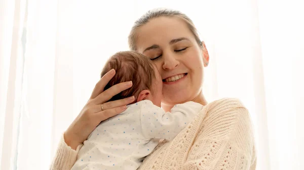 Portrait of happy smiling woman with little baby boy in fornt of big window. Loving and caring parent — Stock Photo, Image