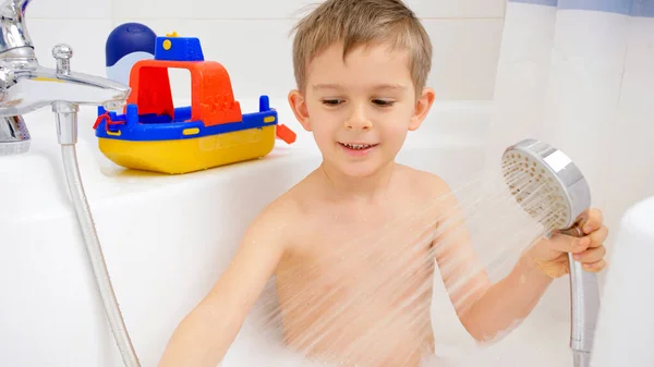 Şirin küçük çocuk köpükle banyo yapıyor ve oyuncaklarla oynuyor. Evde çocuk hijyeni ve sağlık hizmetleri kavramı — Stok fotoğraf