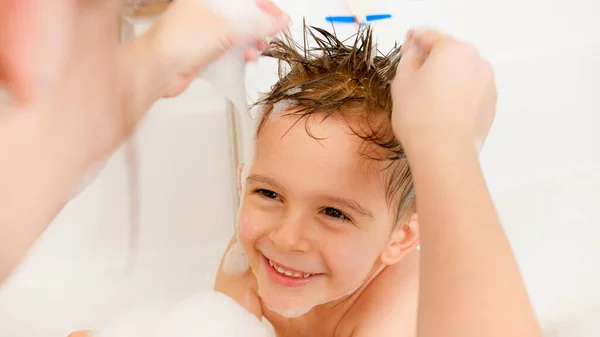 Крупним планом молода мати грає зі своїм маленьким сином, приймаючи ванну і миючи волосся з шампунем. Концепція гігієни дітей та охорони здоров'я вдома. Родина розважається і грає. вдома — стокове фото