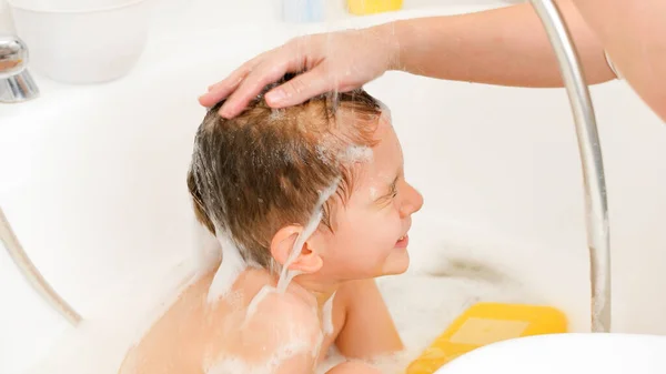 Küçük çocuk şampuanla saç yıkıyor ve duştan sonra su altında oturuyor. Evde çocuk hijyeni ve sağlık hizmetleri kavramı. Aile birlikte vakit geçirir ve evde oynarız.. — Stok fotoğraf