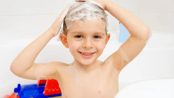 Retrato de un niño pequeño lavándose la cabeza con champú en el baño en casa. Concepto de higiene infantil y atención sanitaria — Foto de Stock