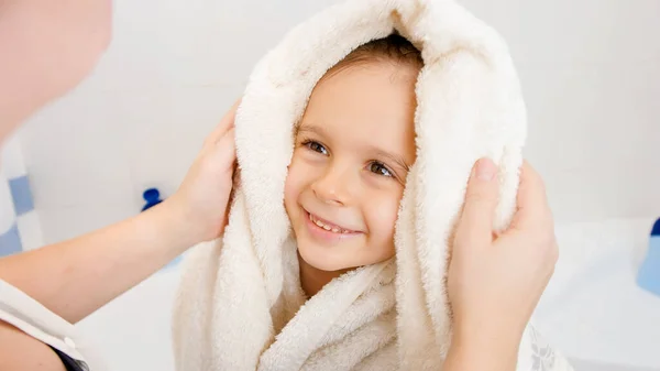 Portrét roztomilého usmívajícího se chlapce s mokrými vlasy utírající a sušení s měkkým ručníkem po koupeli a při pohledu na pečující matku. Koncepce dětské hygieny a zdravotní péče doma. — Stock fotografie