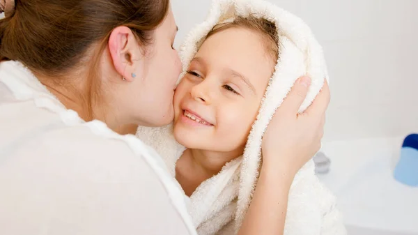 Retrato de la joven madre besando a su pequeño hijo cubierto de toalla blanca después de lavarse en el baño — Foto de Stock