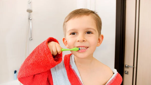 Retrato del niño sonriente en albornoz cepillándose los dientes después de bañarse — Foto de Stock