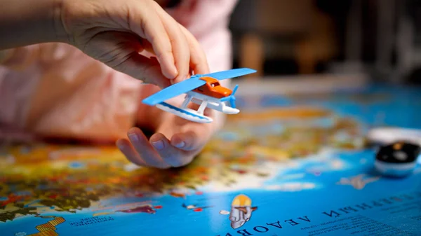 Primer plano del niño jugando con el avión de juguete pequeño en el mapa del mundo grande. Concepto de viajes, turismo y educación infantil. Exploración y descubrimiento infantil —  Fotos de Stock