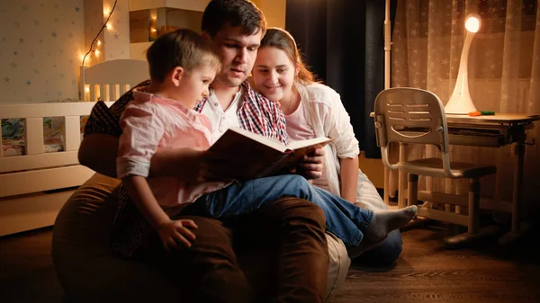 Glückliche Familie mit kleinem Jungen, der abends vor dem Schlafengehen Buch liest. Konzept von Kindererziehung und Familie, die nachts Zeit miteinander verbringen. Stockfoto