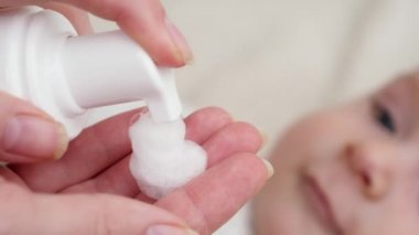 Deri iltihabı ve sivilcelerden muzdarip kırmızı bebek yanağına ilaç losyonu sürmeye yakın. Yeni doğan bebek hijyeni, sağlık ve cilt bakımı kavramı