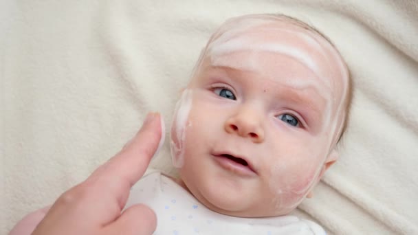 Applicare lozione curativa o unguento su cheecks bambino affetti da dermatite e acne. Concetto di igiene del neonato, salute e cura della pelle — Video Stock