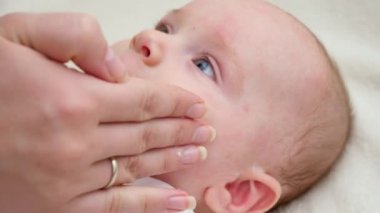 Annenin eli, sivilce ve dermatit yüzünden acı çeken bebeğinin cildine nemlendirici krem sürüyordu. Yeni doğan bebek hijyeni, sağlık ve cilt bakımı kavramı