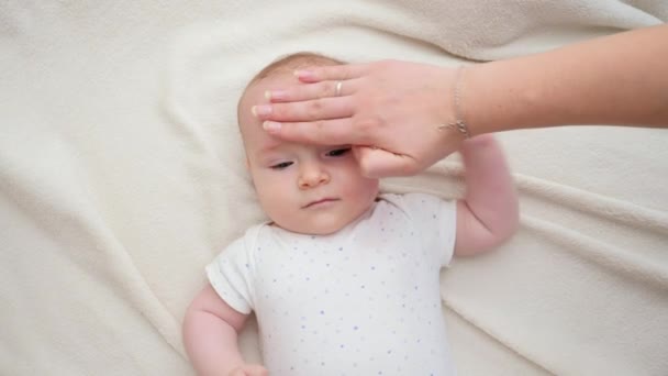 Närbild av mor tillämpa fuktgivande kräm på sin lilla baby ansikte hud. Begreppet nyfödd baby hygien, hälsa och hudvård — Stockvideo