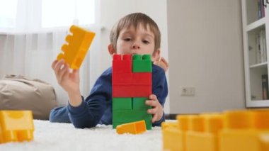 Küçük çocuk renkli plastik oyuncak bloklardan yüksek kule inşa ediyor. Evde çocuk eğitimi ve oyun kavramı