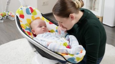 Mutlu gülümseyen anne, evdeki elektrikli sandalyede oturan küçük oğluyla oynuyor. Çocuk gelişimi ve mutlu ebeveynlik