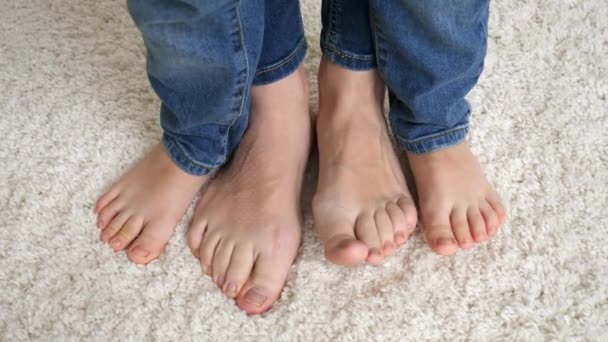 Nahaufnahme einer barfüßigen Mutter mit kleinem Sohn auf weißem Teppich und beweglichen Zehen. — Stockvideo