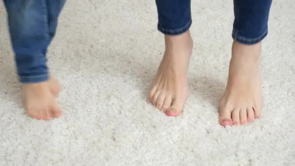 Pendekatan ibu bertelanjang kaki dengan anak kecil melompat dan bermain di karpet putih lembut — Stok Video