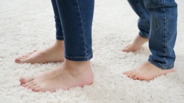 Крупним планом дитячі ноги б'ють матерів стоять на білому килимі — стокове відео