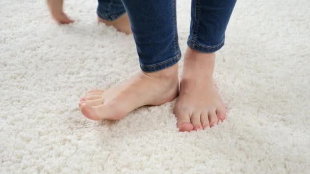 Closeup of barefoot little boy playing and running around mother standing on soft white carpet. — Stock Video