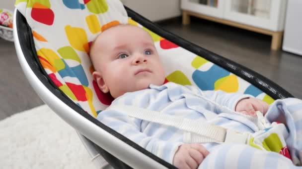 Mignon petit garçon couché et relaxant dans une chaise berçante colorée dans le salon. Développement de l'enfant et enfance — Video