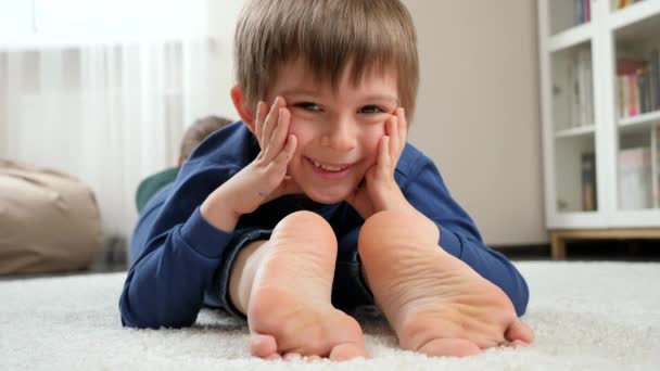 Portret van een blije lachende jongen die op moeders voeten ligt en in de camera kijkt. Familie die plezier hebben en samen spelen — Stockvideo