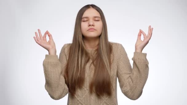 Portret van het kalmerende meisje en het maken van meditatie gebaar over witte achtergrond — Stockvideo