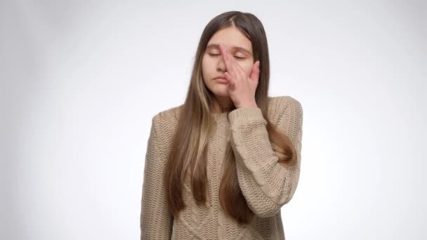 Chica triste limpiando lágrima con la mano y mirando hacia arriba sobre fondo blanco estudio — Vídeos de Stock