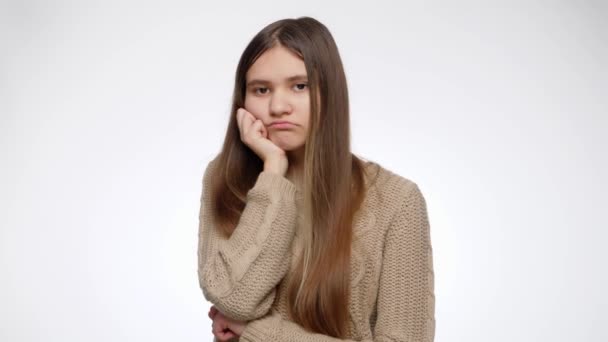 Giel se siente aburrida sosteniendo su barbilla con la mano sobre el fondo blanco del estudio — Vídeos de Stock