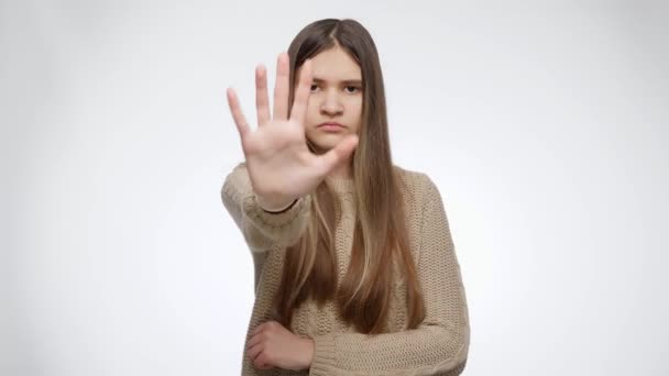 Retrato de chica seria mostrando stop o ningún gesto con la mano sobre fondo de estudio blanco — Vídeo de stock